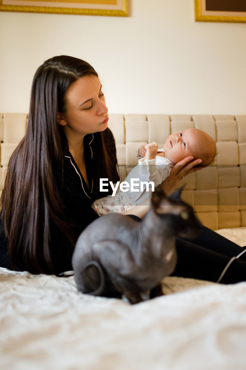 Mother with baby sitting on bed at home