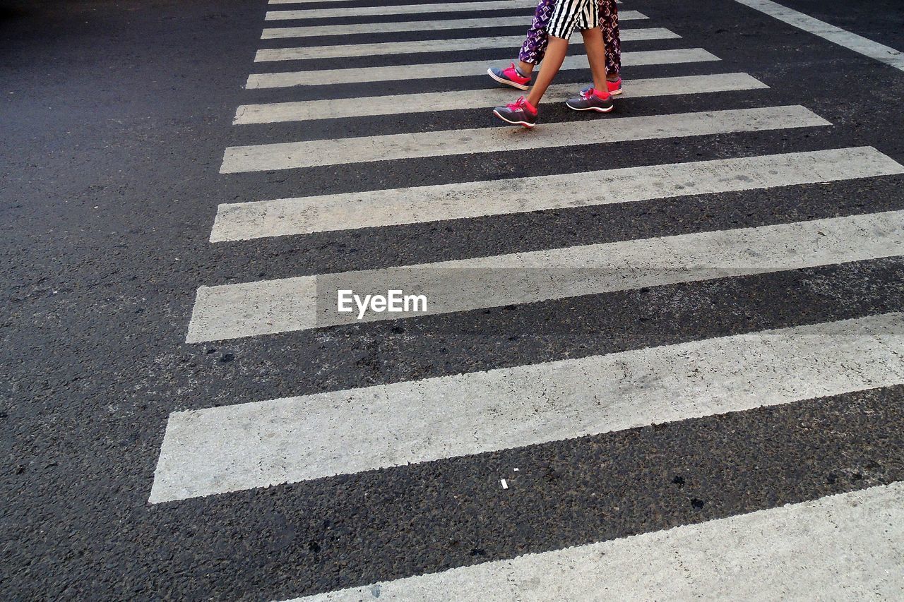 Low section of people walking on zebra crossing