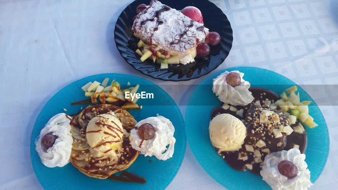 High angle view of desserts served in plates on table