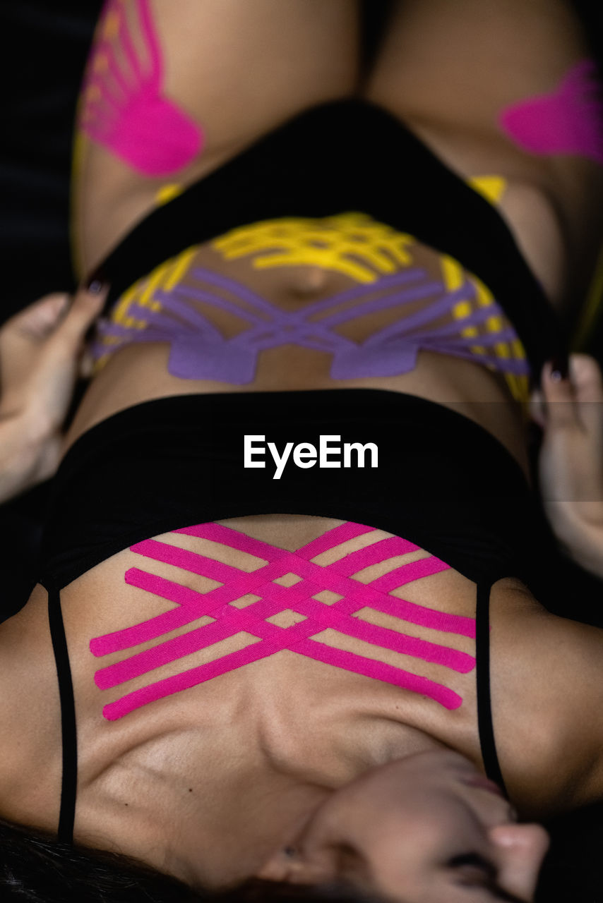 Cosmetology kinesio tapes on young woman abdomen and chest. body care