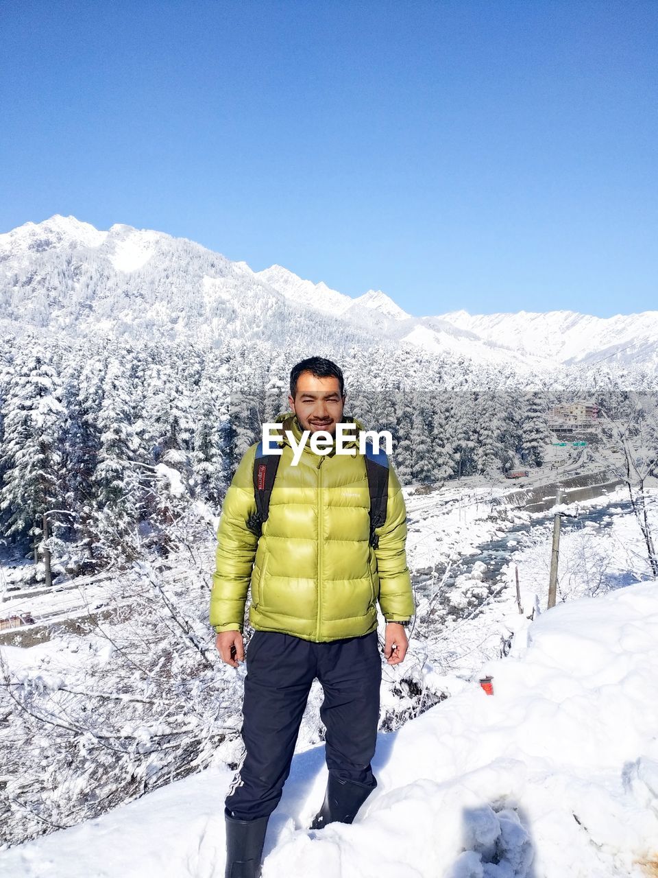 PORTRAIT OF YOUNG WOMAN STANDING ON SNOWCAPPED MOUNTAIN