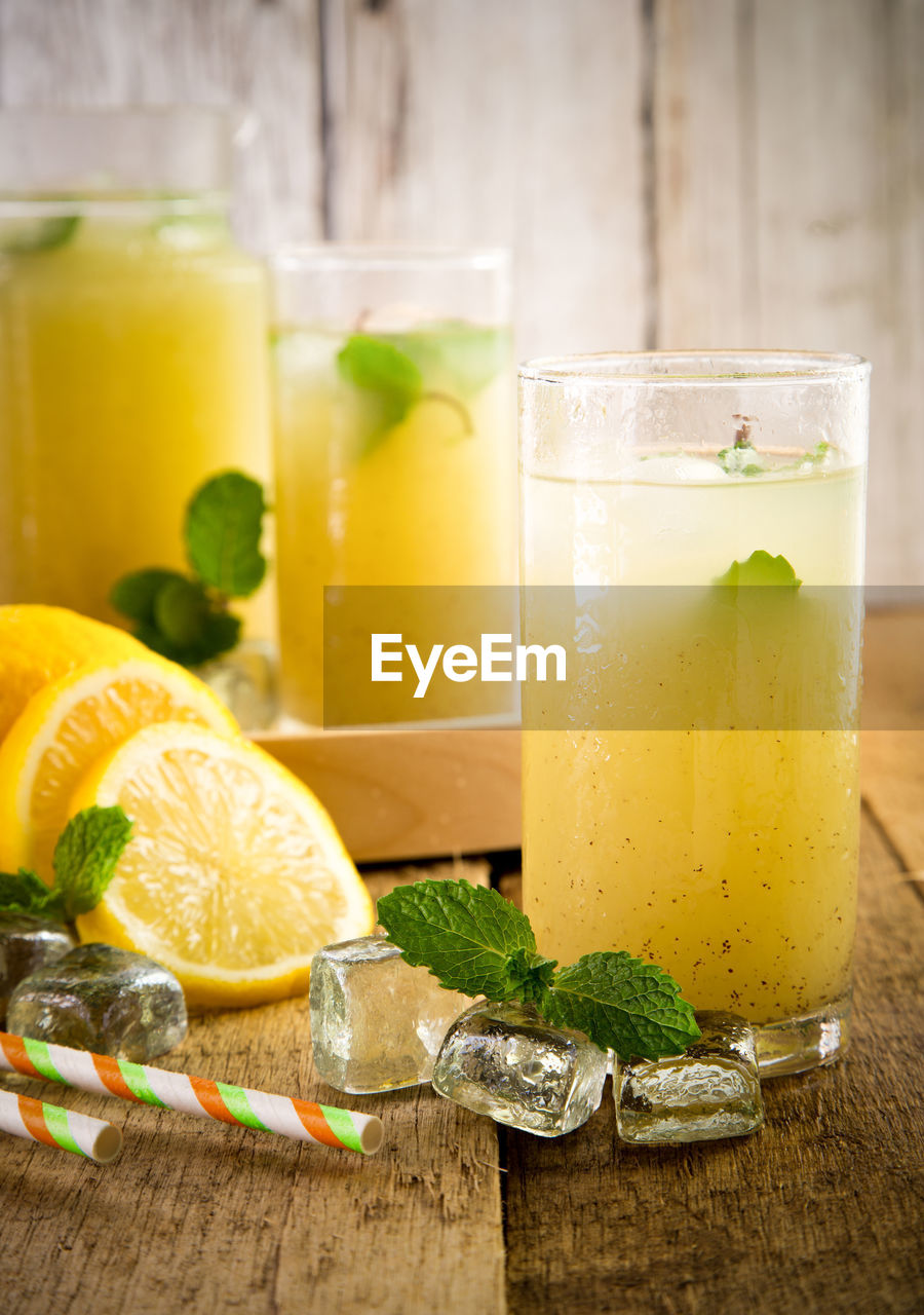 Fruit juice in glasses by lemon slices on table