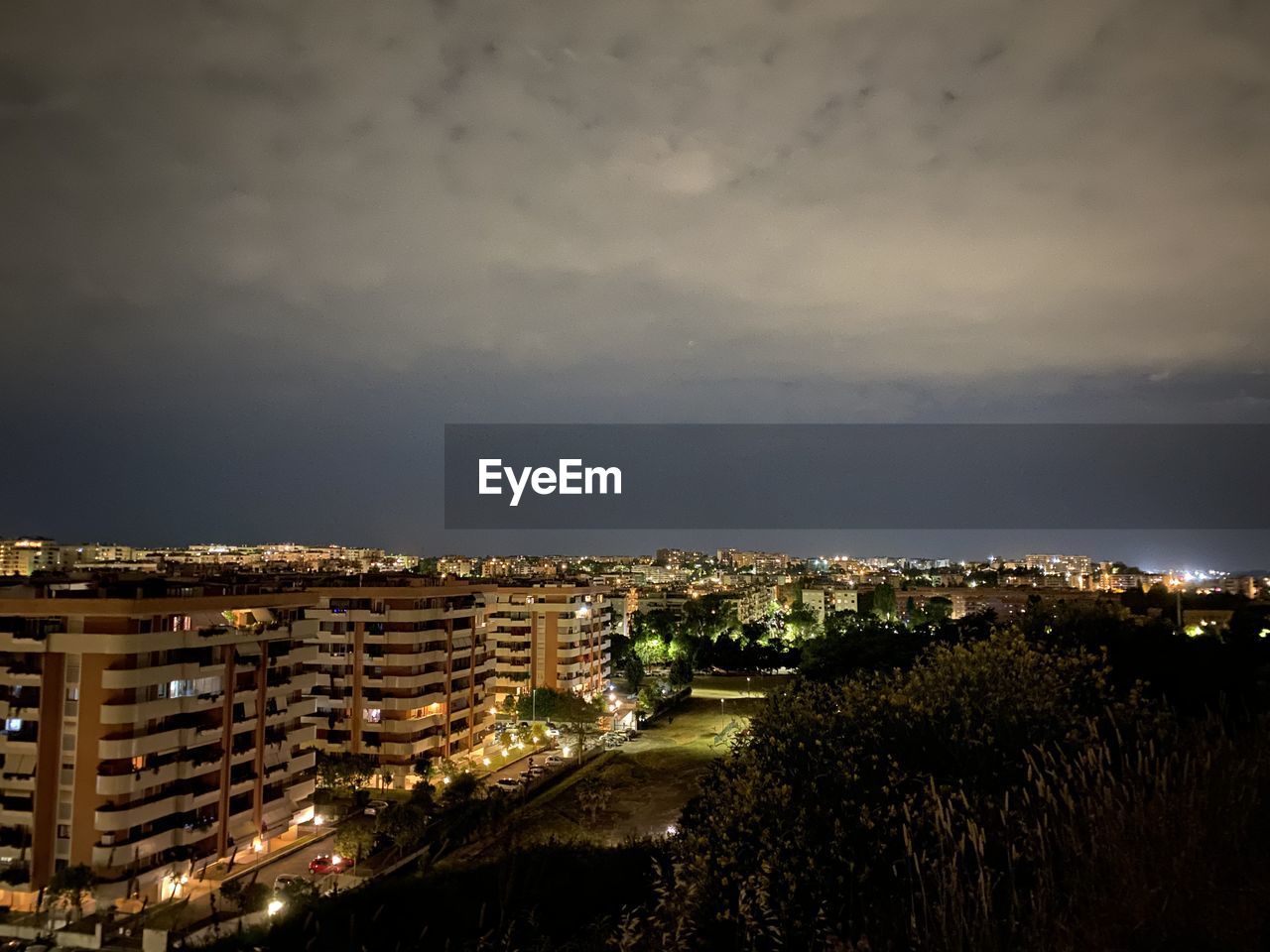 HIGH ANGLE VIEW OF ILLUMINATED BUILDINGS IN CITY AT NIGHT