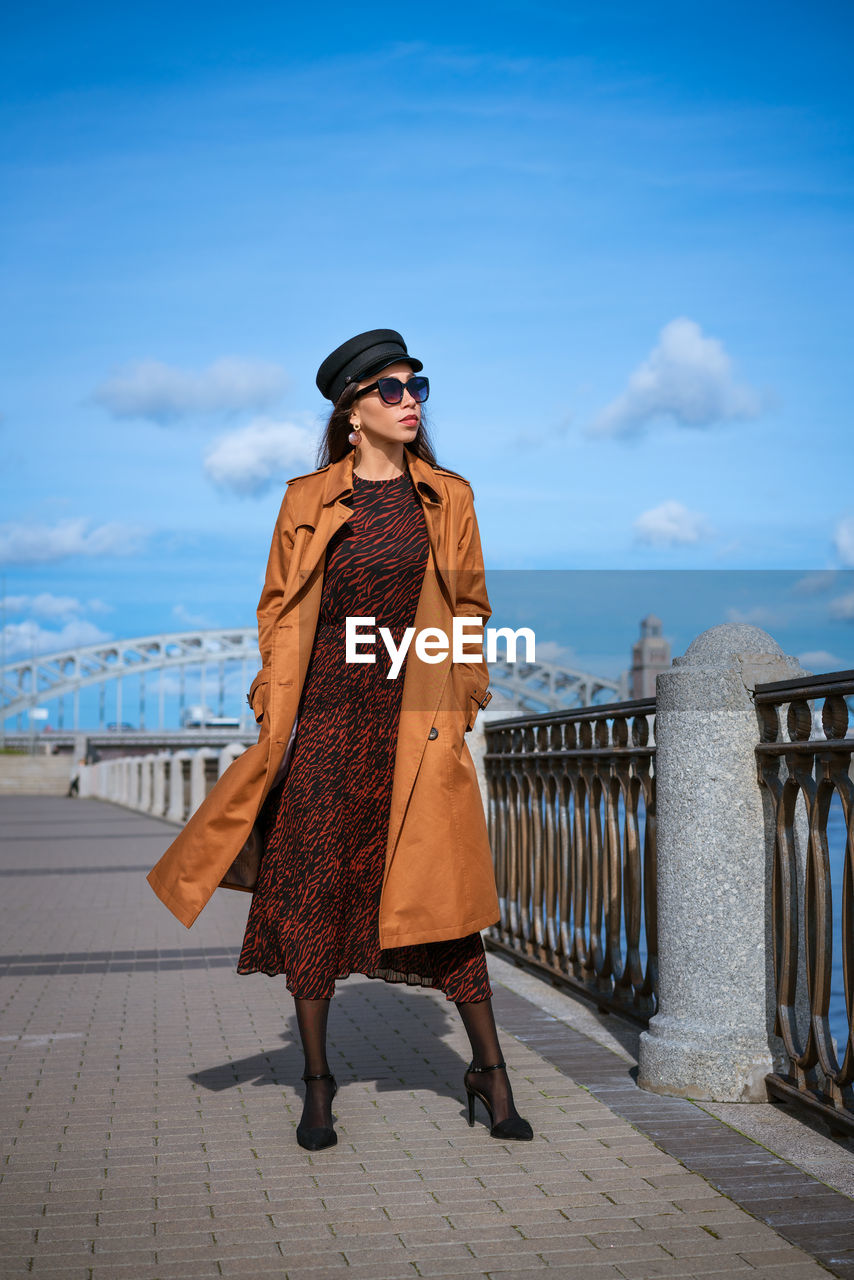 Beautiful young woman in a raincoat on the embankment