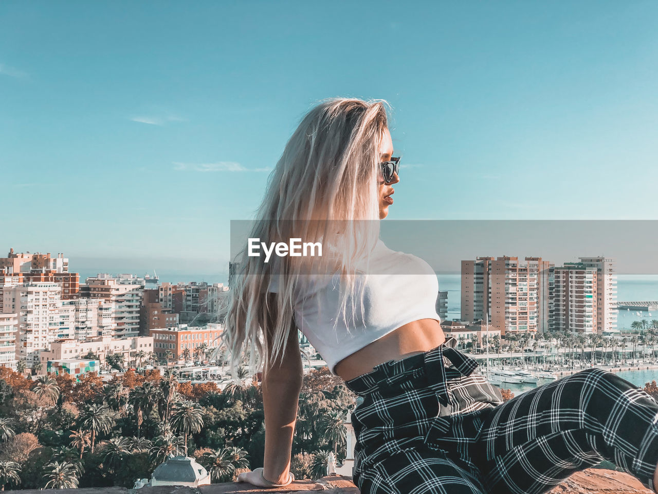 WOMAN LOOKING AT CITYSCAPE AGAINST BUILDINGS