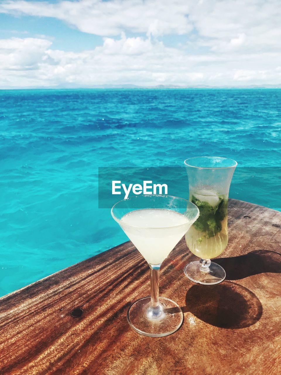 VIEW OF DRINK ON TABLE AGAINST SEA