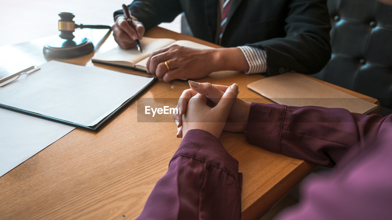Lawyer talking to female while sitting by table in office