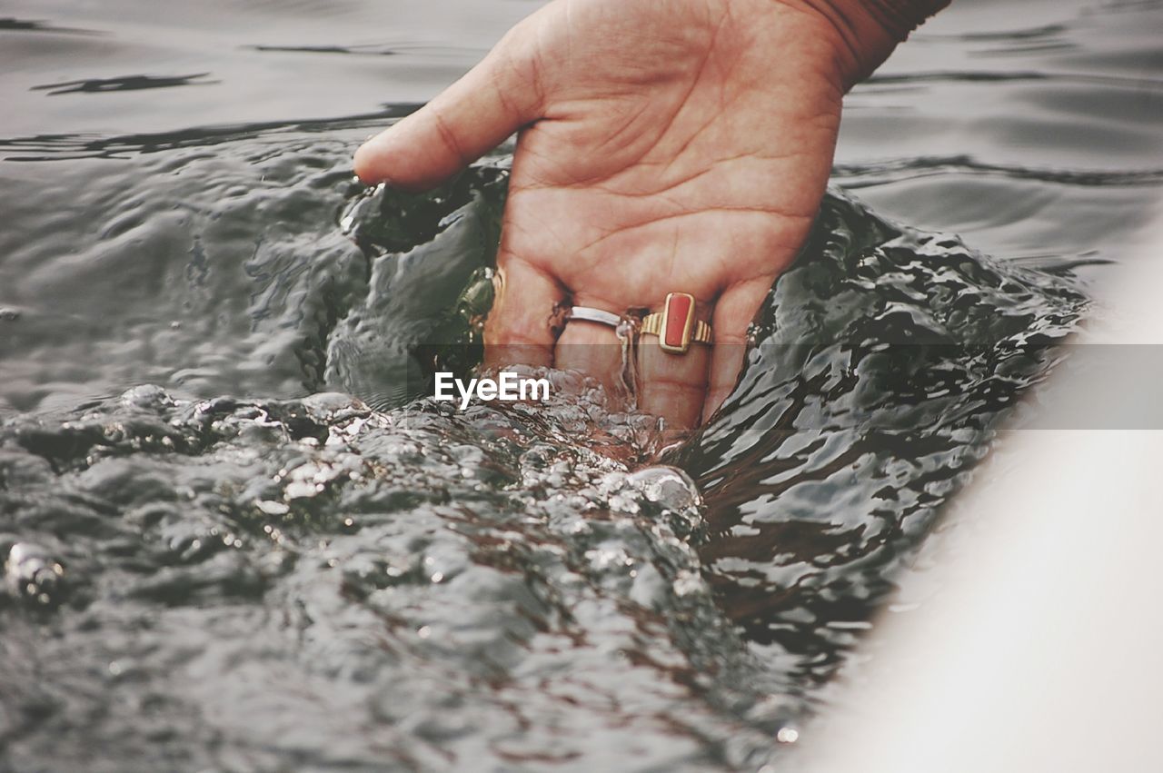 Cropped hand touching water in lake