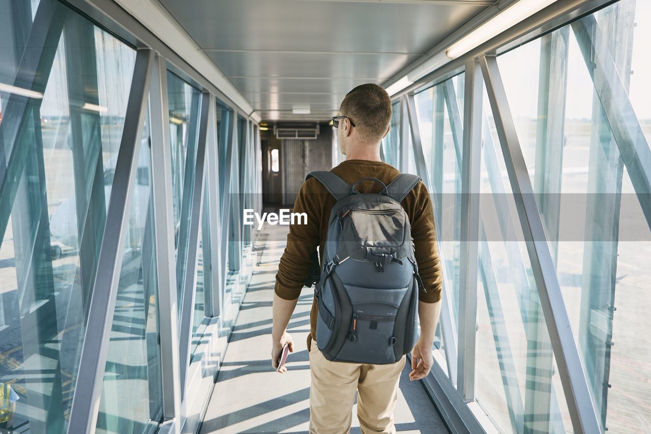 Rear view of man walking in passenger boarding bridge