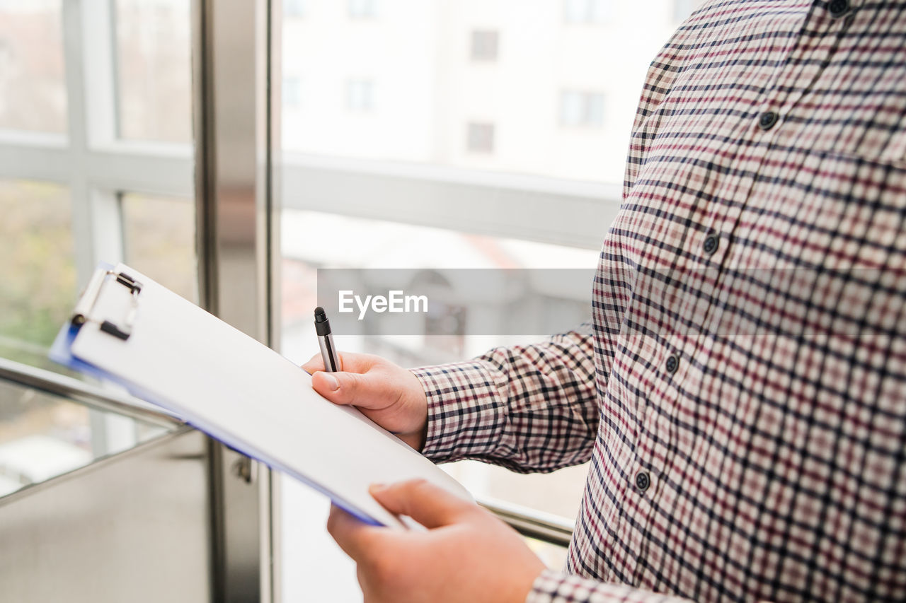 Midsection of man holding paper at office