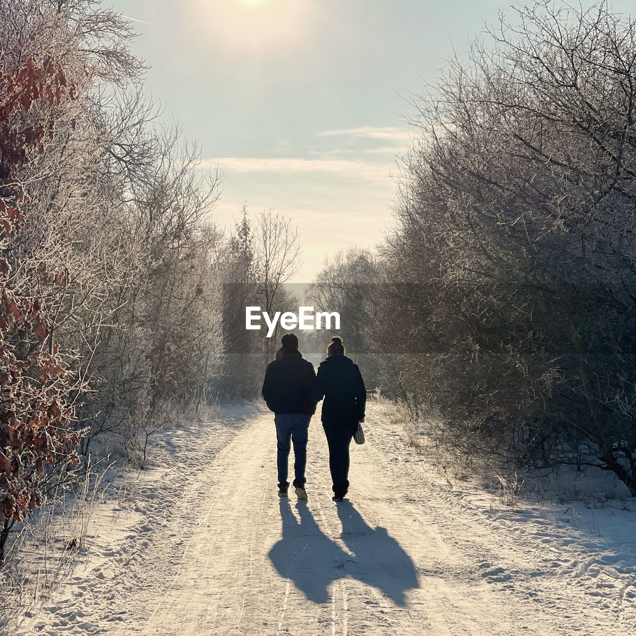 REAR VIEW OF MEN WALKING ON SNOW COVERED FIELD