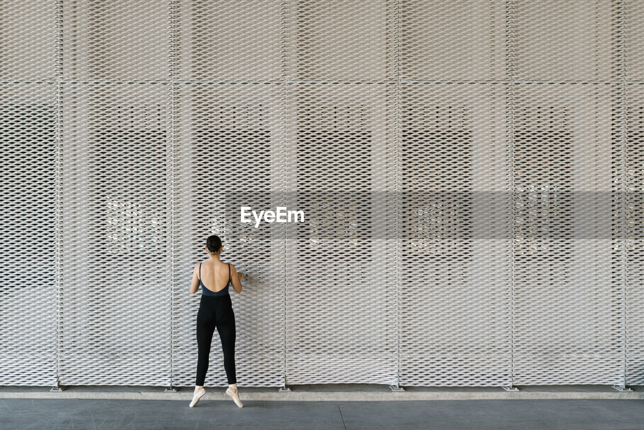 Female ballet dancer practicing in front of metal wall