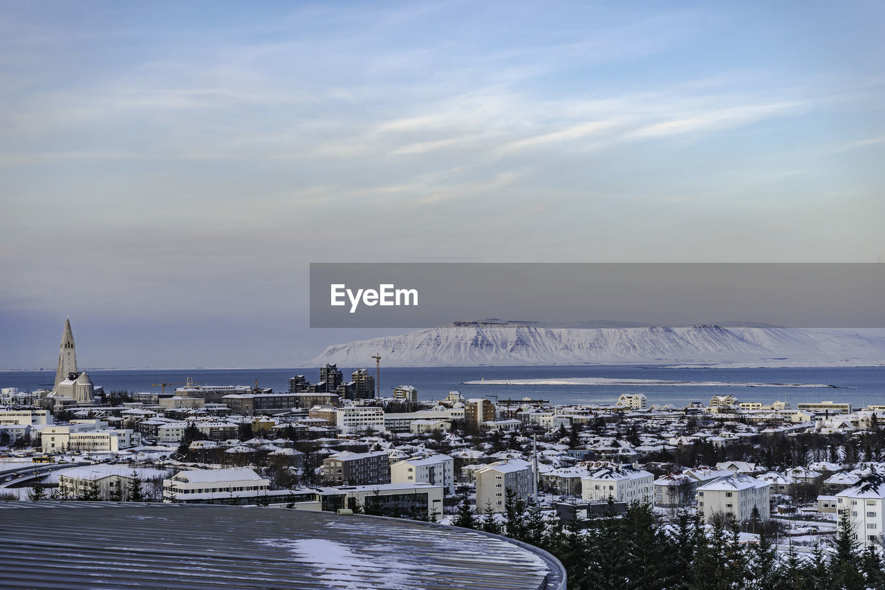 High angle view of town by sea against sky