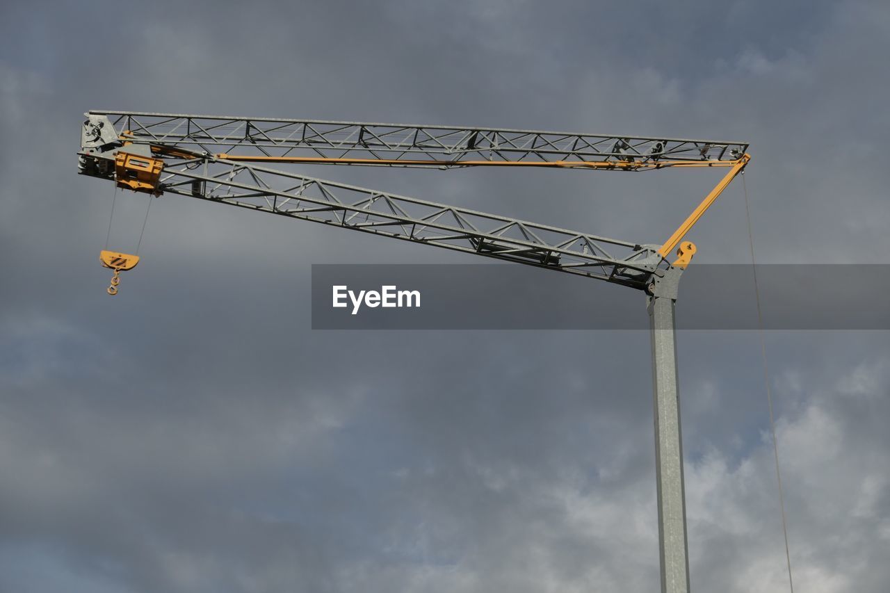 Low angle view of crane against cloudy sky