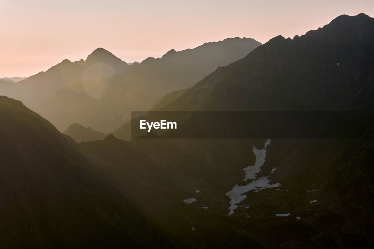 mountain, environment, landscape, scenics - nature, mountain range, nature, sky, beauty in nature, land, travel, sunset, fog, mountain peak, sun, travel destinations, panoramic, tranquility, no people, silhouette, sunlight, outdoors, forest, valley, dawn, plant, twilight, tourism, activity, tree, wilderness, tranquil scene, trip, vacation, cloud, holiday, non-urban scene, ridge, sunbeam, rural scene, summer, social issues, environmental conservation