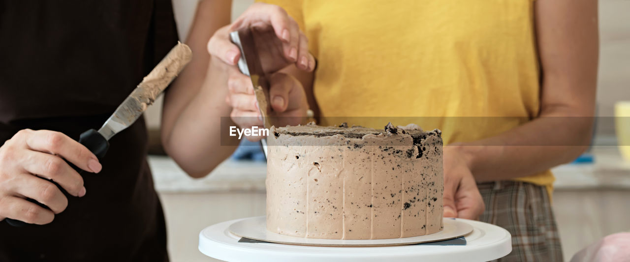 Women couple making chocolate cake in kitchen, close-up. cake making process, selective focus