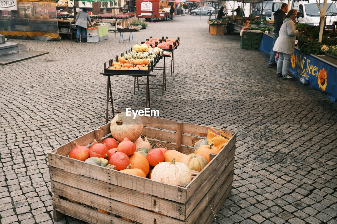 food and drink, food, healthy eating, public space, city, market, freshness, fruit, retail, wellbeing, container, vegetable, market stall, street, architecture, business, basket, day, large group of objects, orange color, abundance, transportation, outdoors, crate, box, tomato, variation, no people, for sale, high angle view