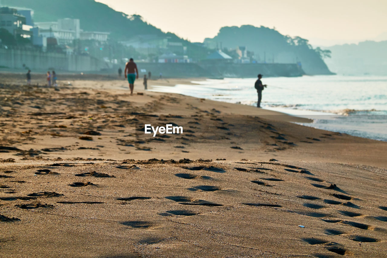 People walking on beach against sky