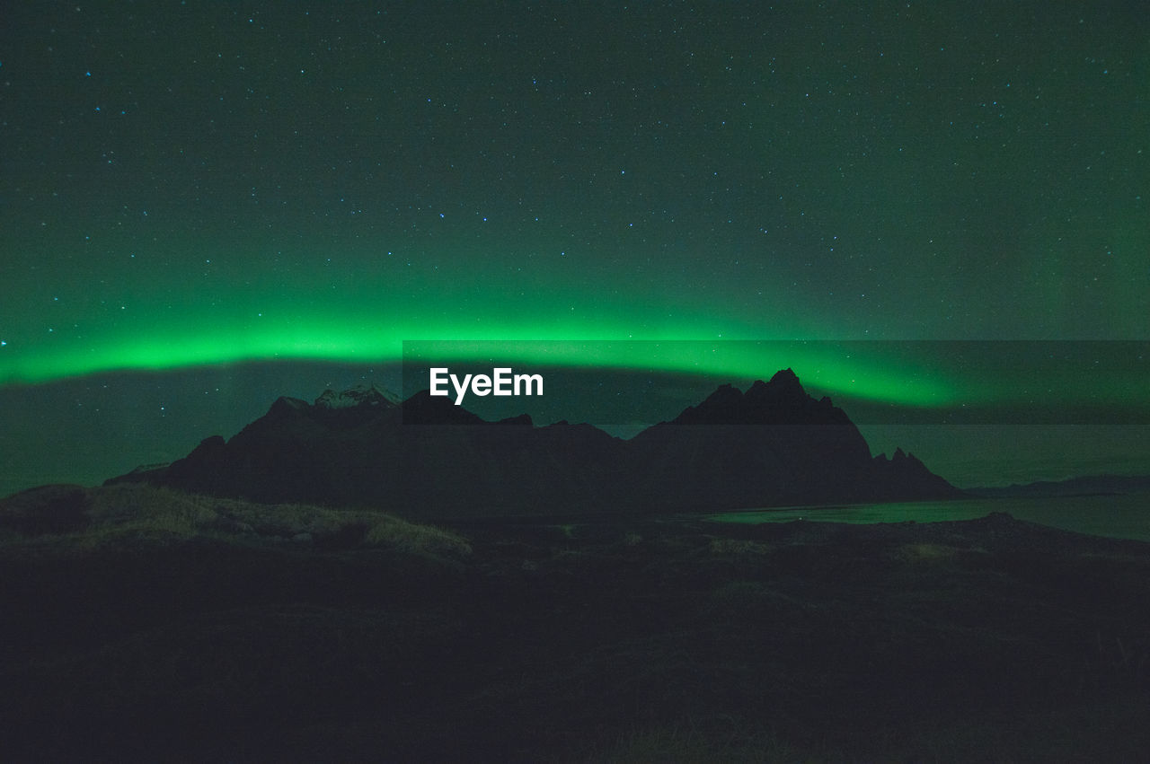 Scenic view of mountains with aurora against sky at night