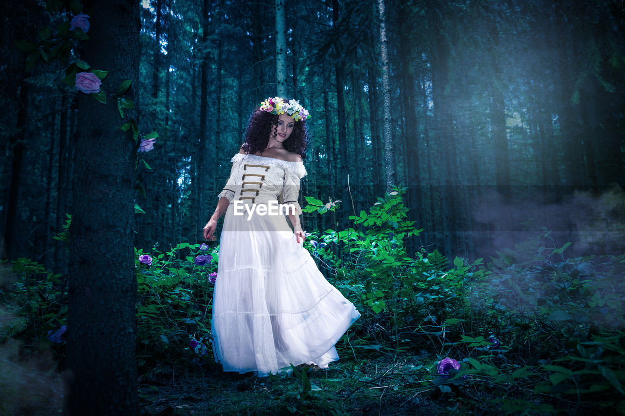 Woman wearing white dress while standing in forest