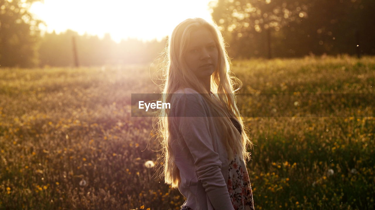 WOMAN STANDING ON GRASSY FIELD