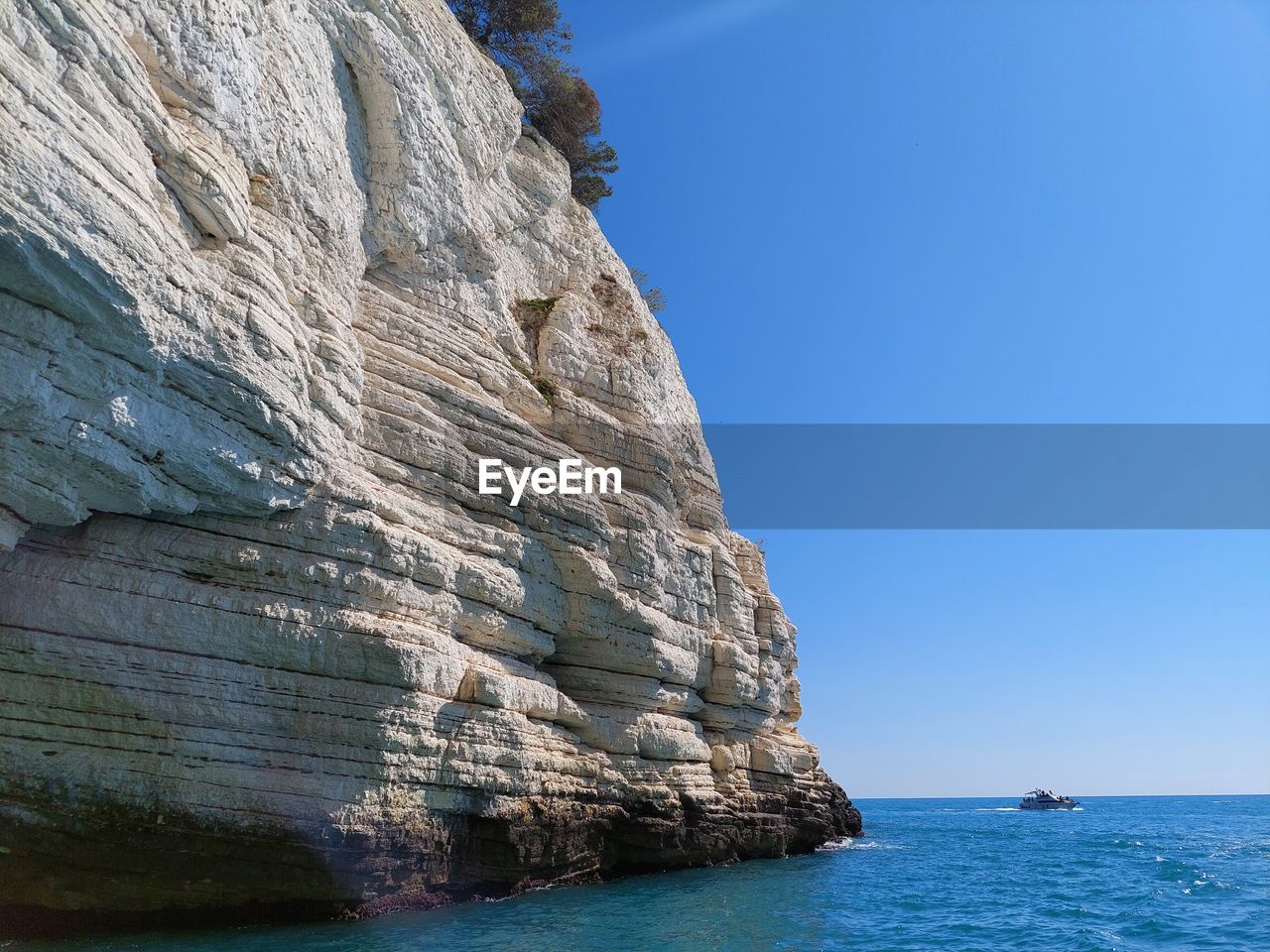 ROCK FORMATION IN SEA AGAINST CLEAR SKY