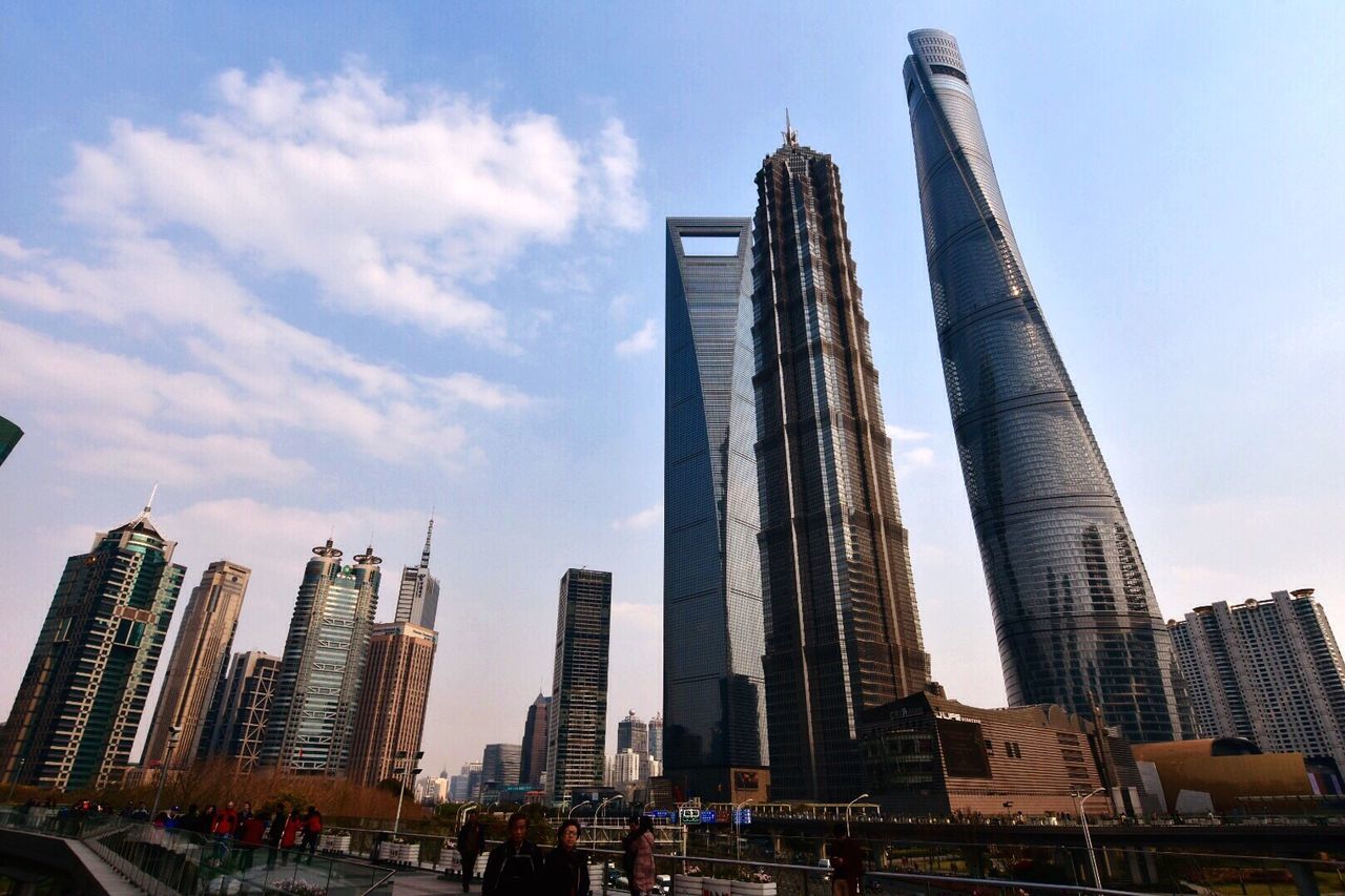 People walking on footpath against shanghai tower and modern buildings