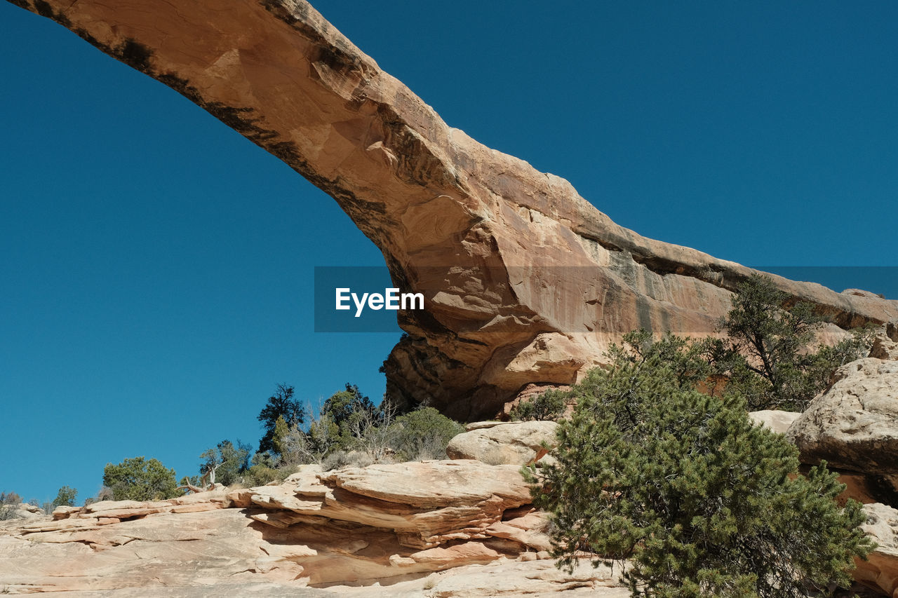 Low angle view of rock formation against clear blue sky