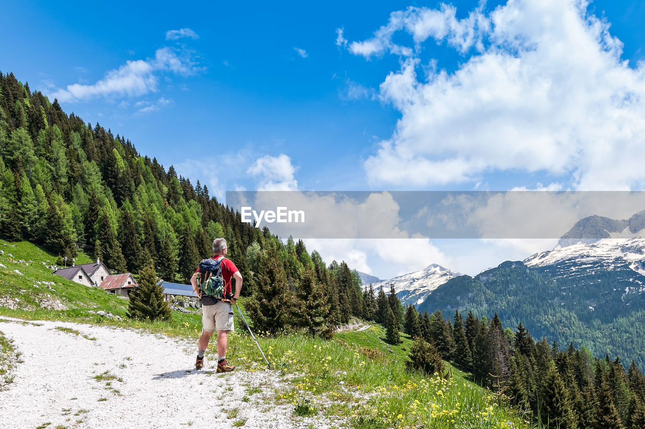 Rear view of backpacker looking at mountains against sky