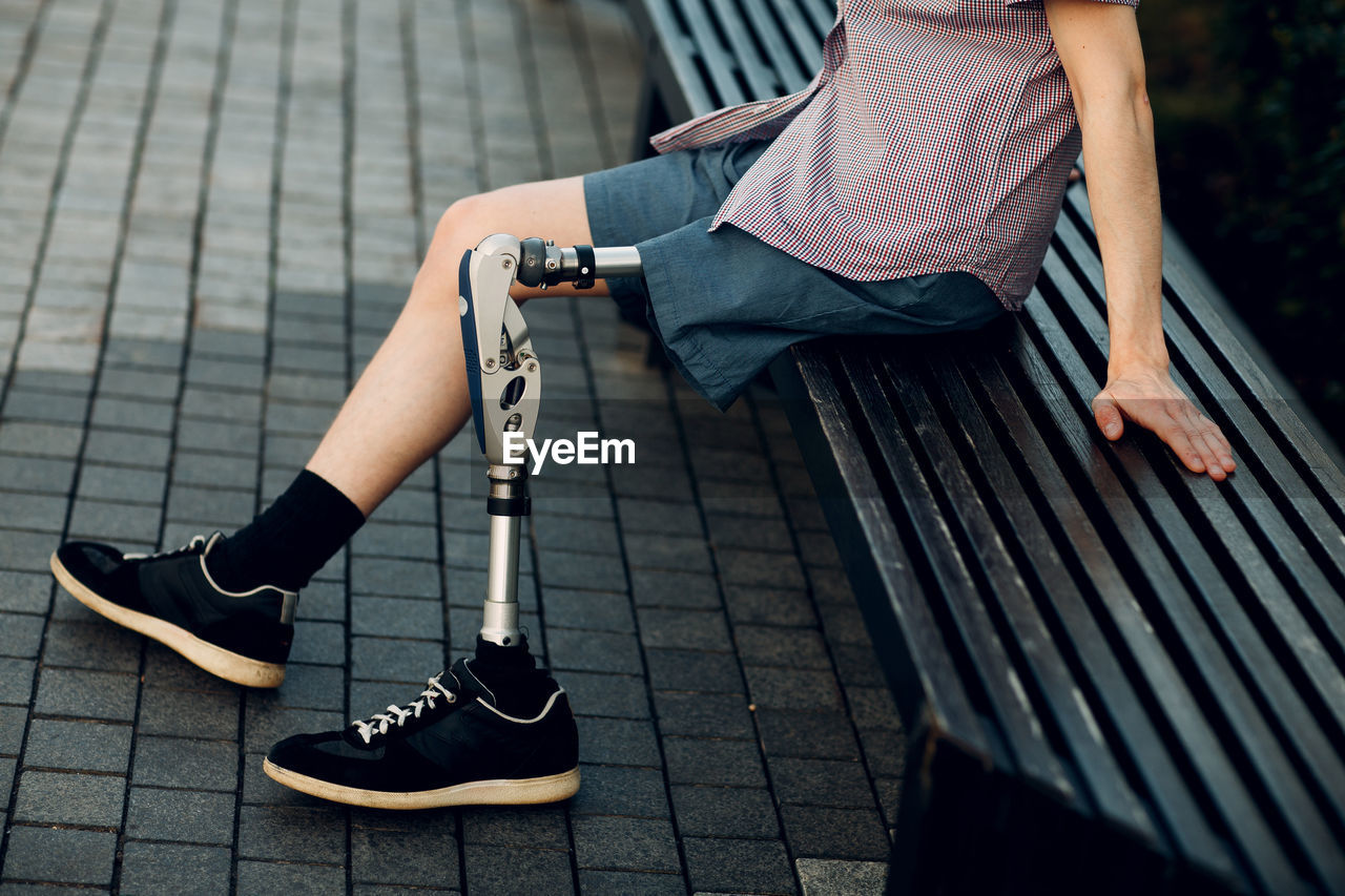 Low section of woman sitting on footpath