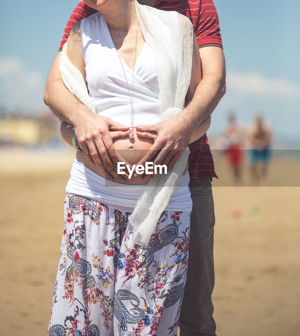 Pregnant woman and husband making heart shape sign