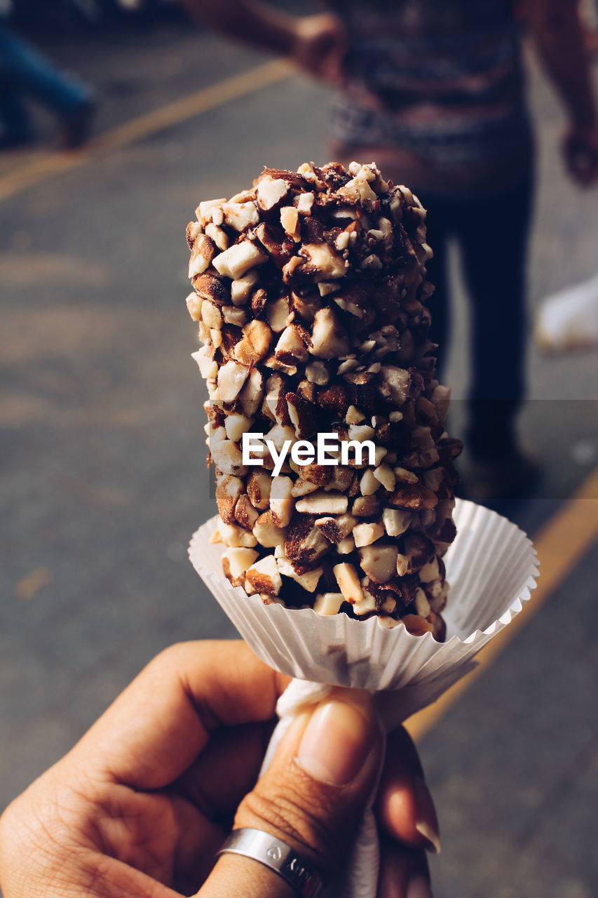 Cropped image of woman holding ice cream candy on city street