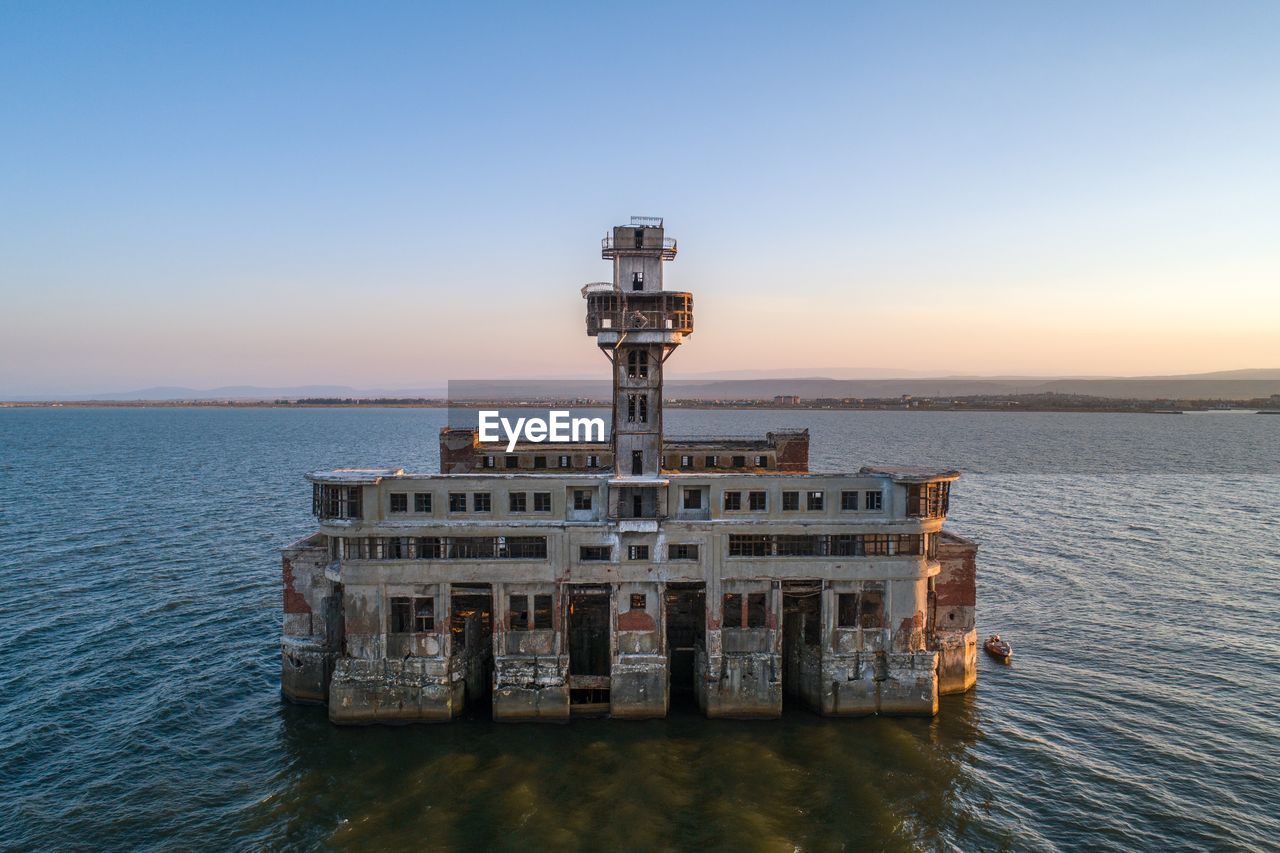 Built structure by sea against clear sky