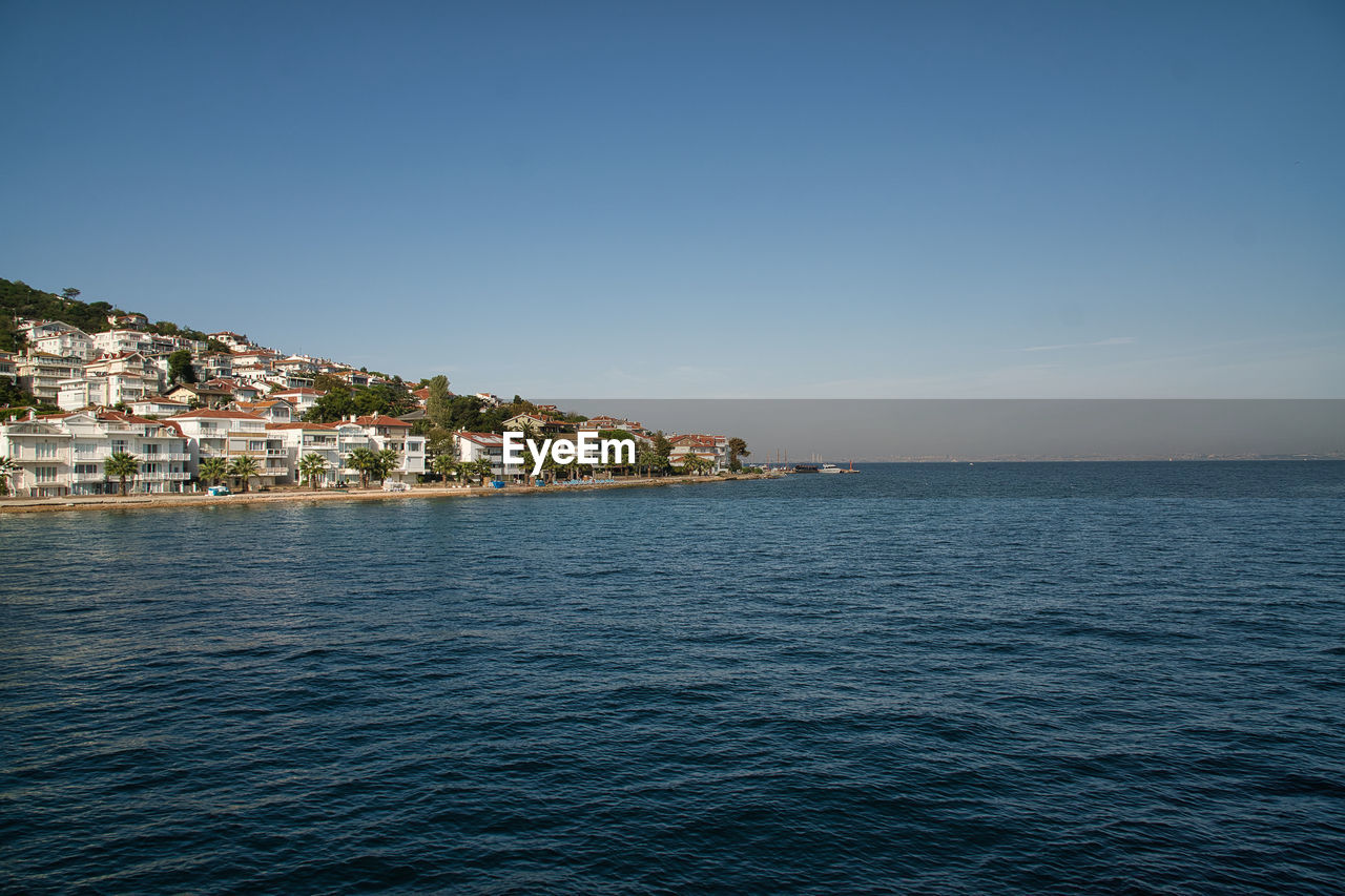 Scenic view of sea by townscape against sky
