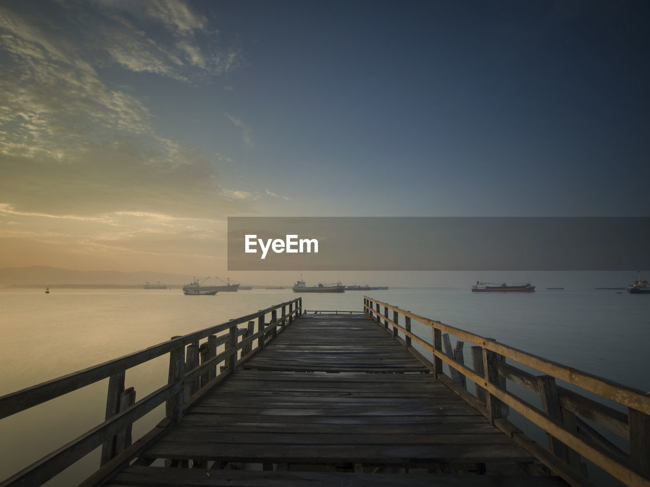 Pier over sea against sky during sunset