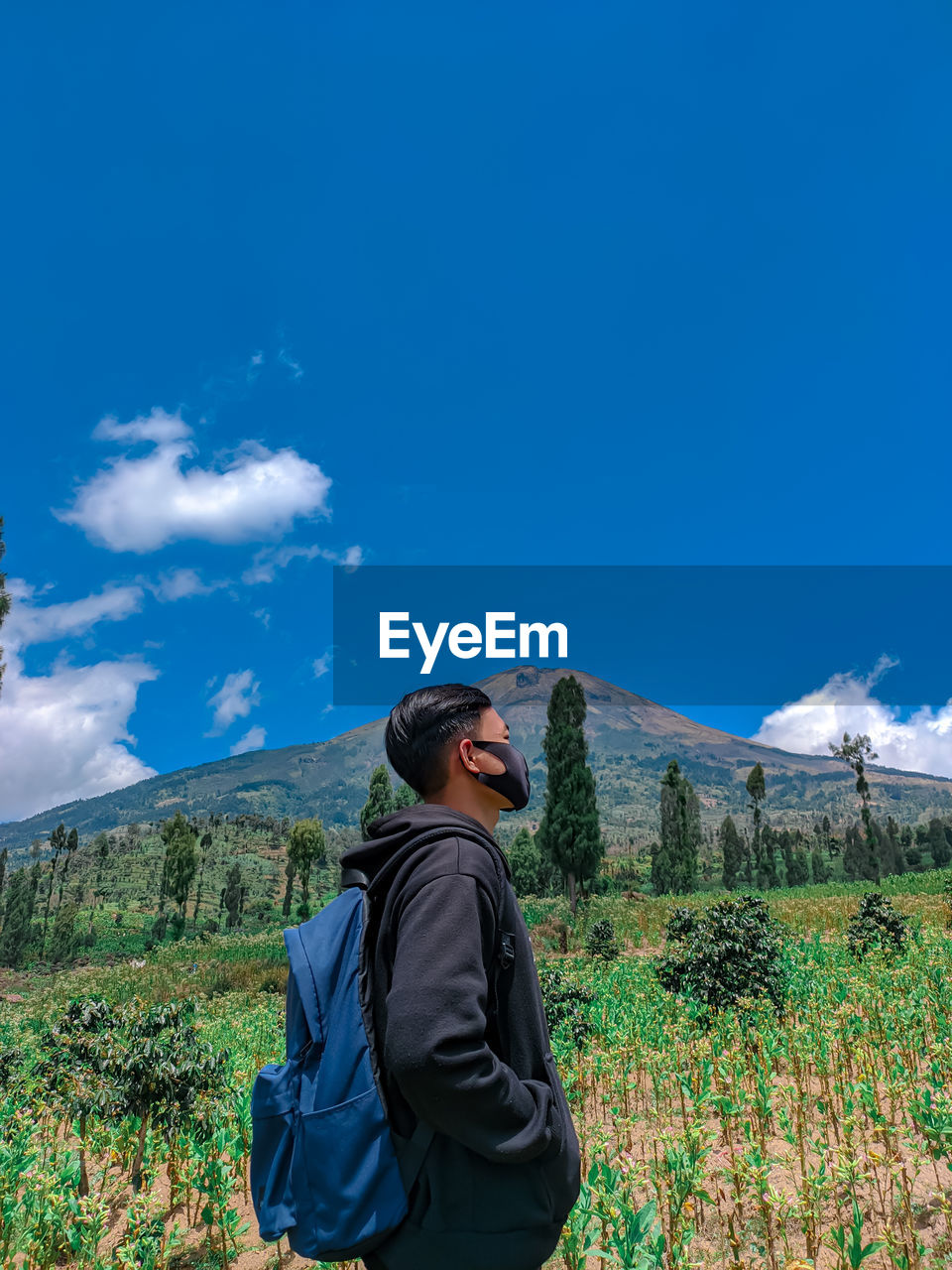 Young man standing against mountain and sky