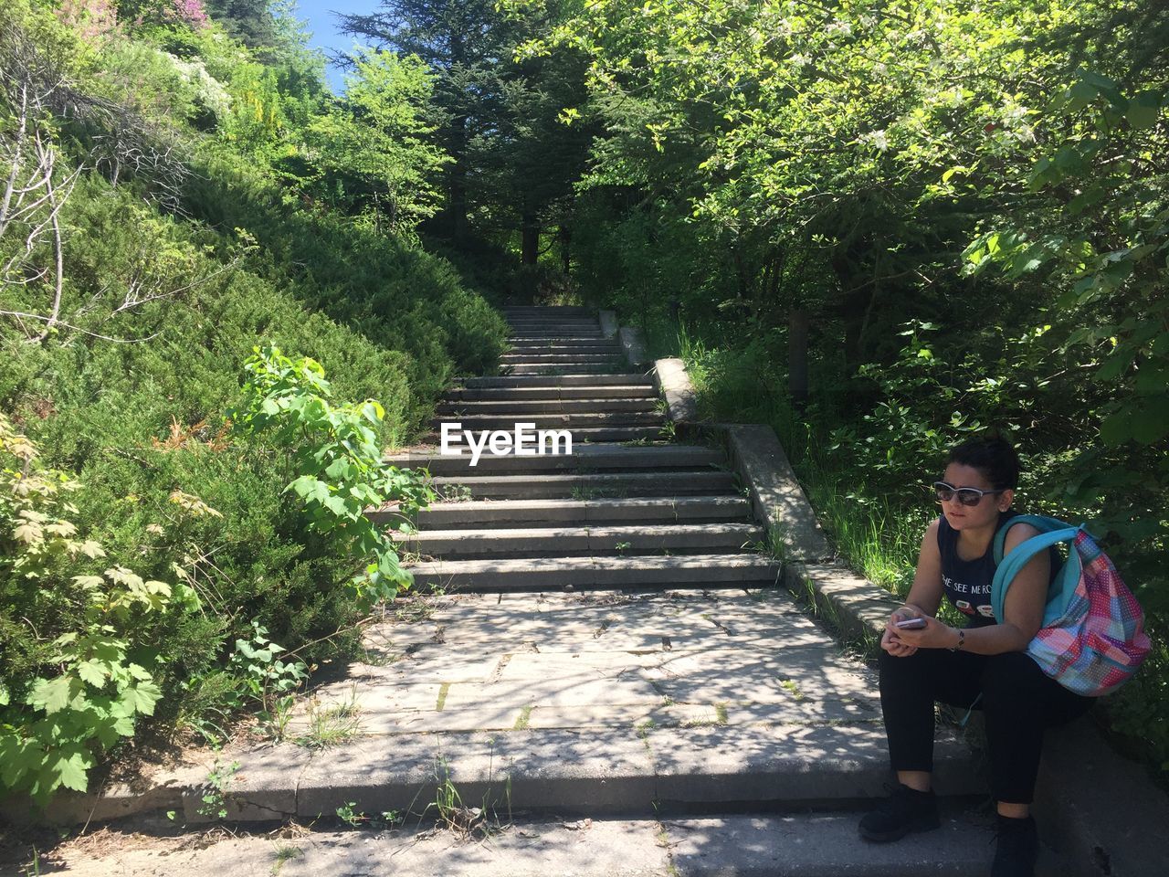 WOMAN SITTING ON STAIRCASE AT PARK