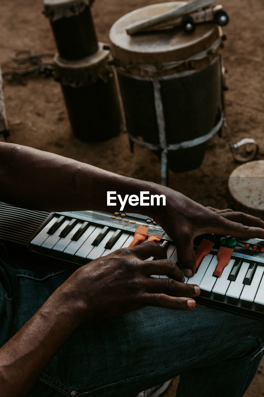 Midsection of man playing piano while sitting outdoors