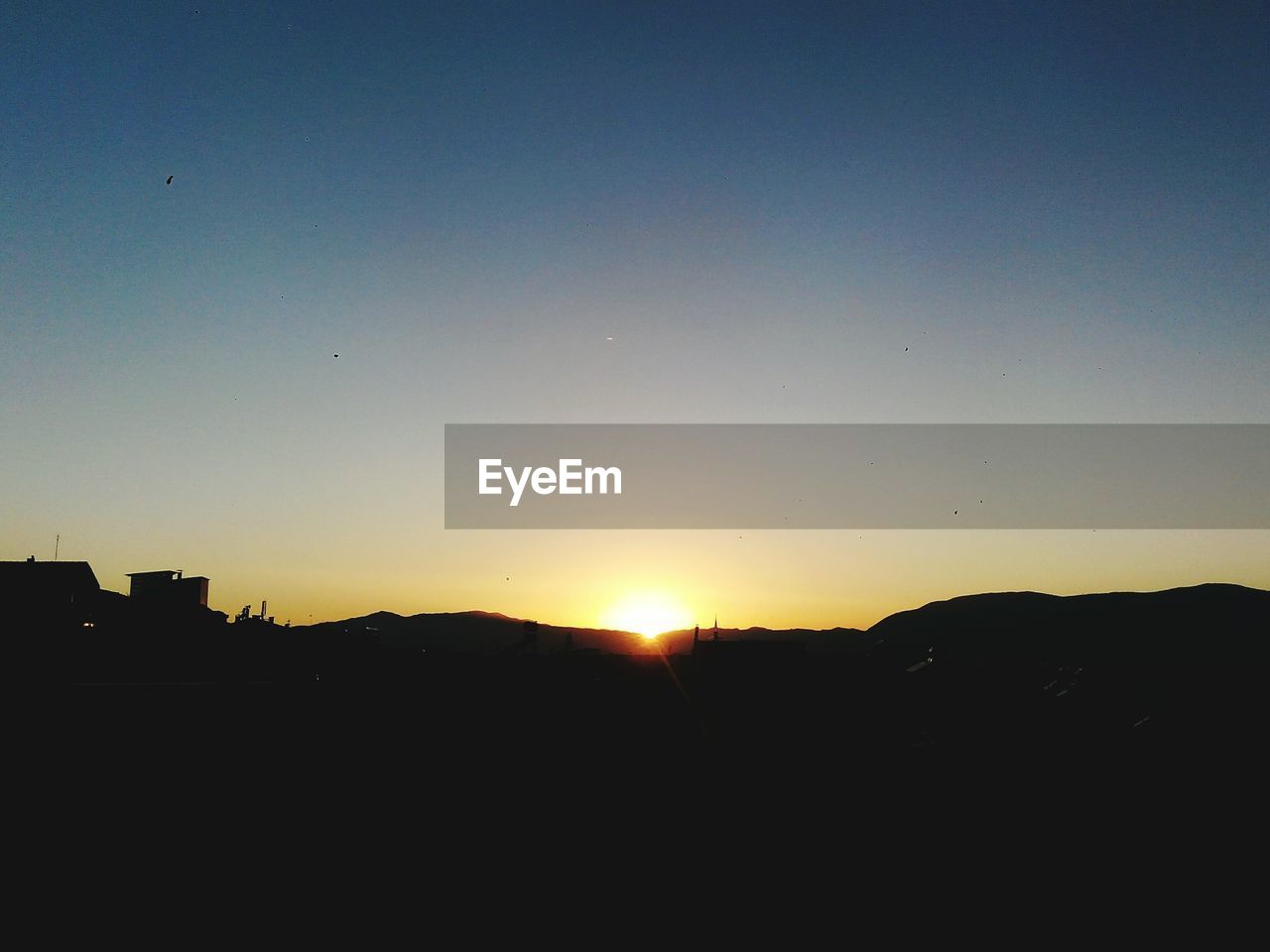 Silhouette landscape against clear sky at sunset