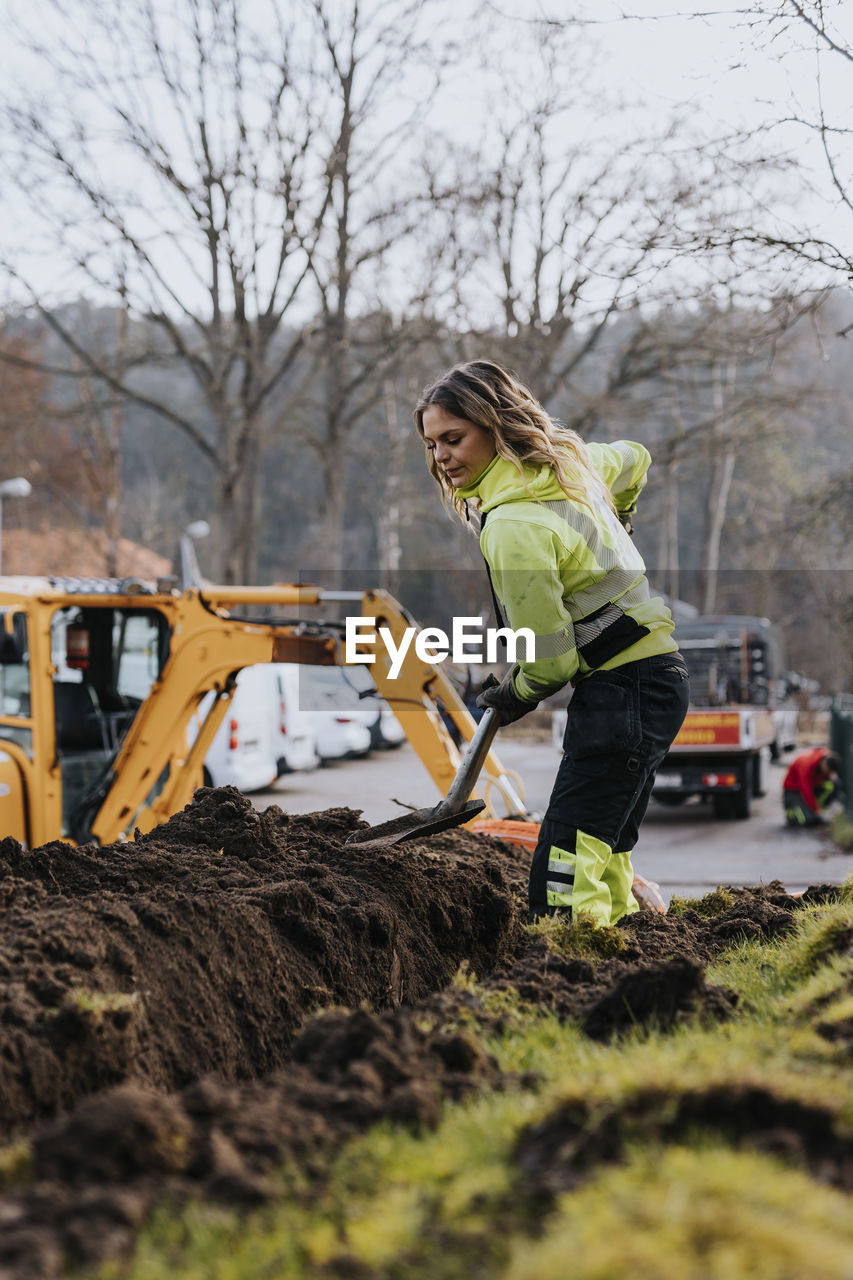 Young female worker digging trench