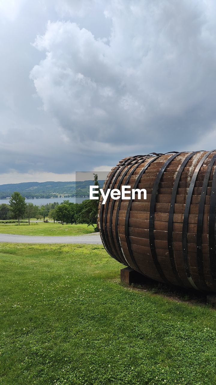 barrel, cloud, grass, sky, plant, nature, agriculture, refreshment, landscape, green, food and drink, field, drink, alcohol, wine, cylinder, no people, land, environment, wine cask, rural scene, winemaking, day, winery, wine cellar, outdoors, cellar, rural area, tree, wood, container, lawn, scenics - nature