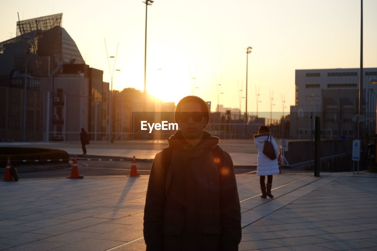 Portrait of man standing on footpath at sunset