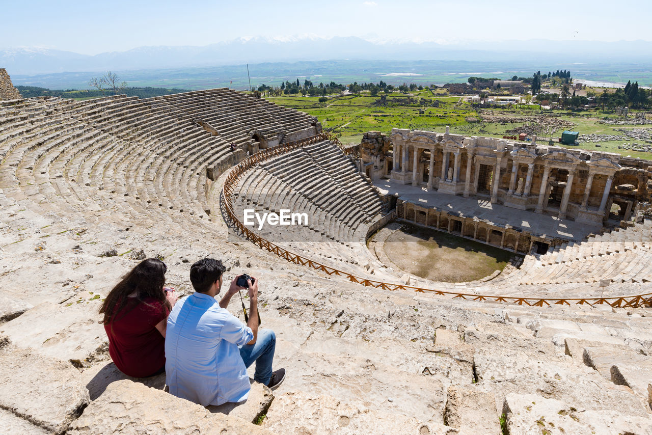 HIGH ANGLE VIEW OF PEOPLE SITTING ON OLD RUIN