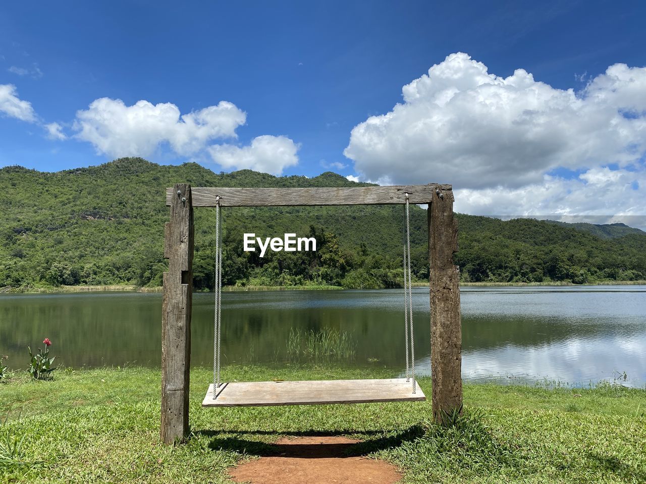 Wooden posts on field by lake against sky