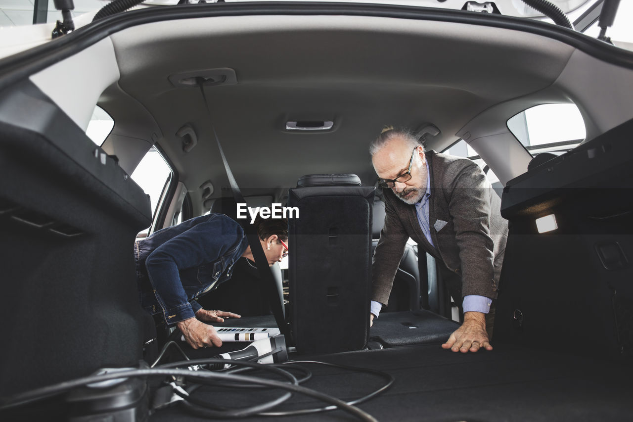 Senior man and woman examining inside new car at showroom