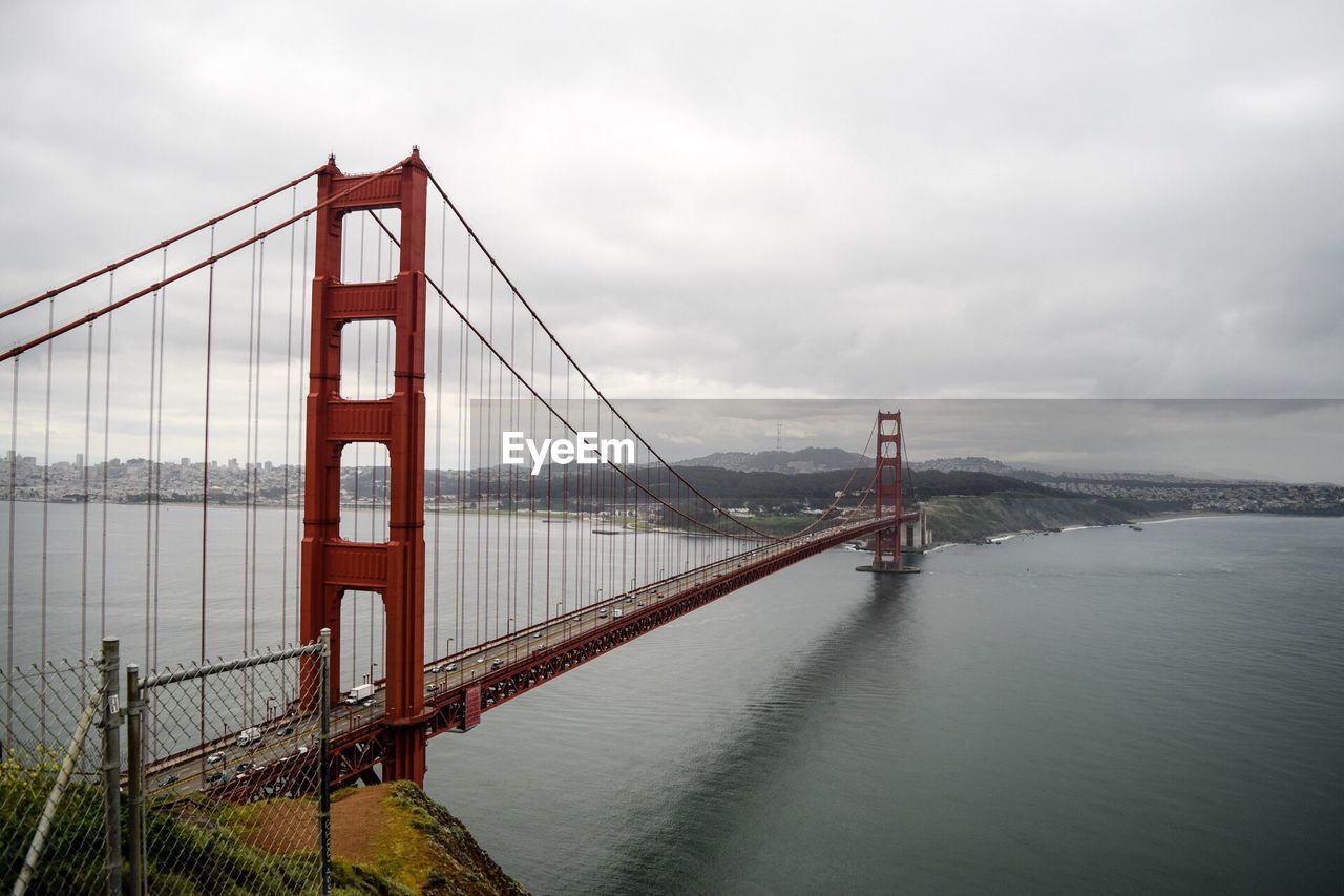 Golden gate bridge over river against cloudy sky