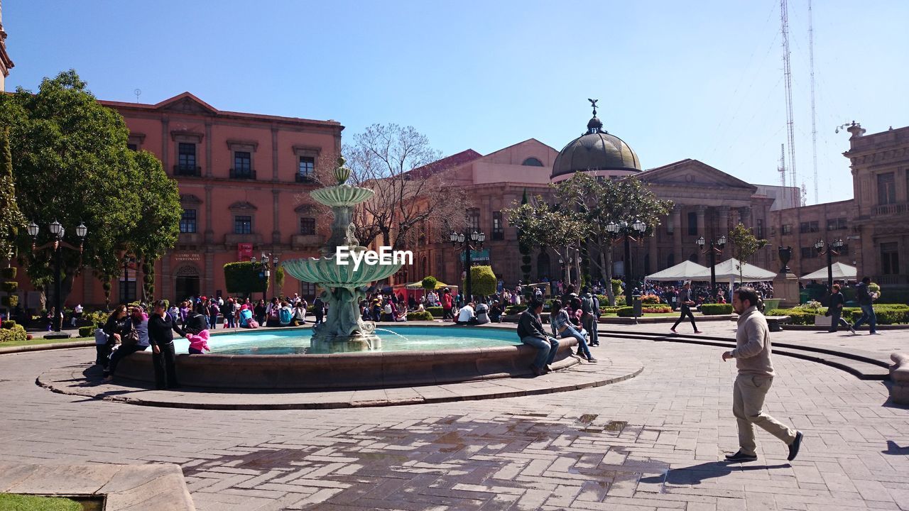 PEOPLE BY SWIMMING POOL AGAINST CLEAR SKY