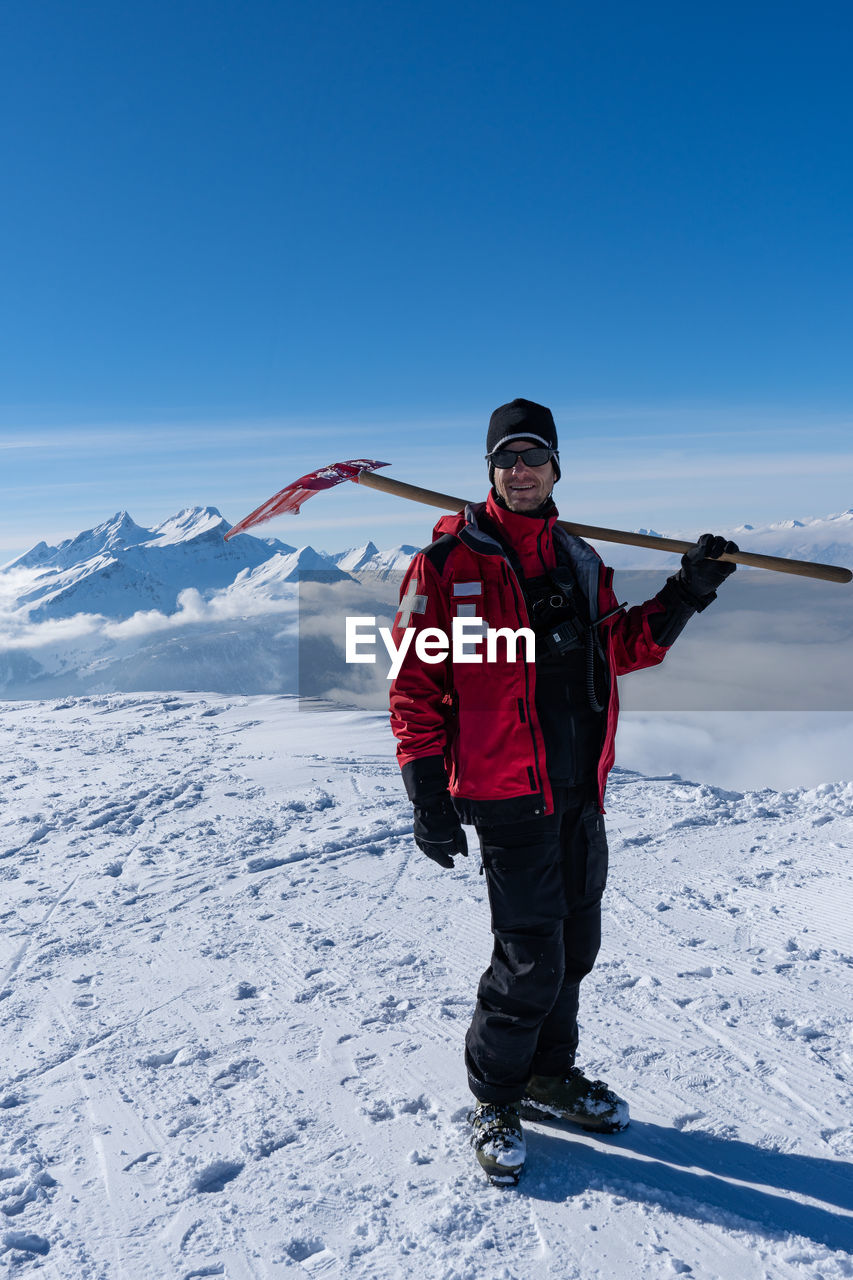 Full length of man standing on snowcapped mountain against sky