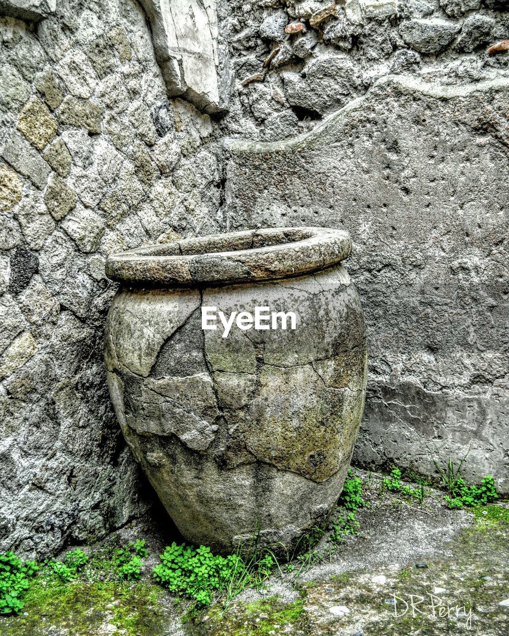 Damaged abandoned urn against wall