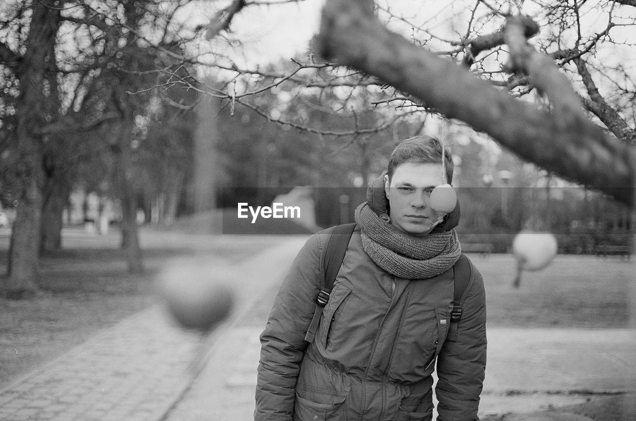 Portrait of man standing by tree during winter